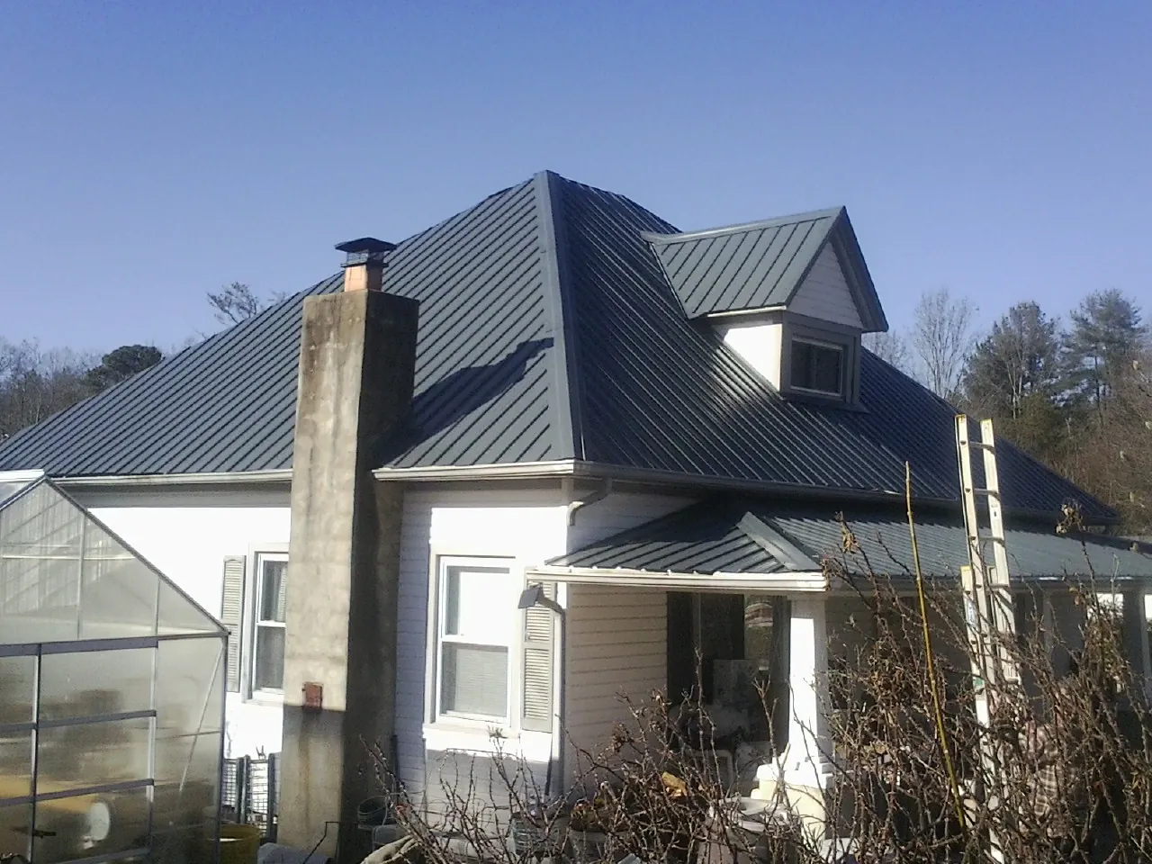 Dark blue standing seam metal roof on a white farmhouse with dormer — Slate & Tile Roof Repair by Roofing Brothers in Bergen