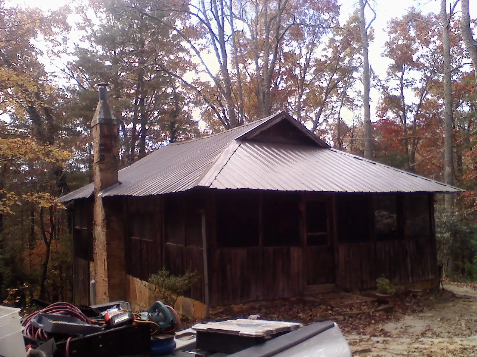 Brown metal hip roof on an old cabin with a stone chimney in Bergen