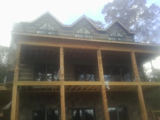 Dormers and porch framing on a large log home under construction — Roof Coating work by our crew in Bergen
