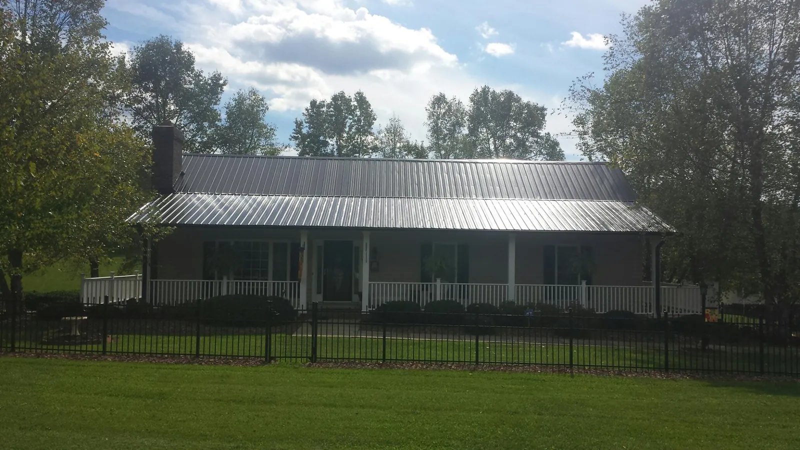 Gray metal roof on a brick ranch with a full width front porch — Gutter Guard Installation work by our crew in Bergen