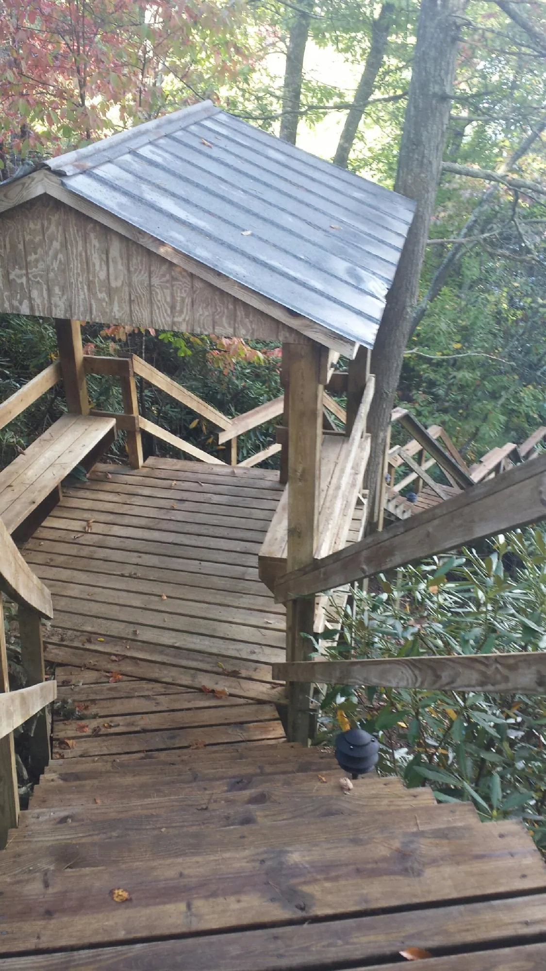 Metal roofed shelter over wooden steps on a wooded walkway — Skylight Repair & Installation work by our crew in Bergen