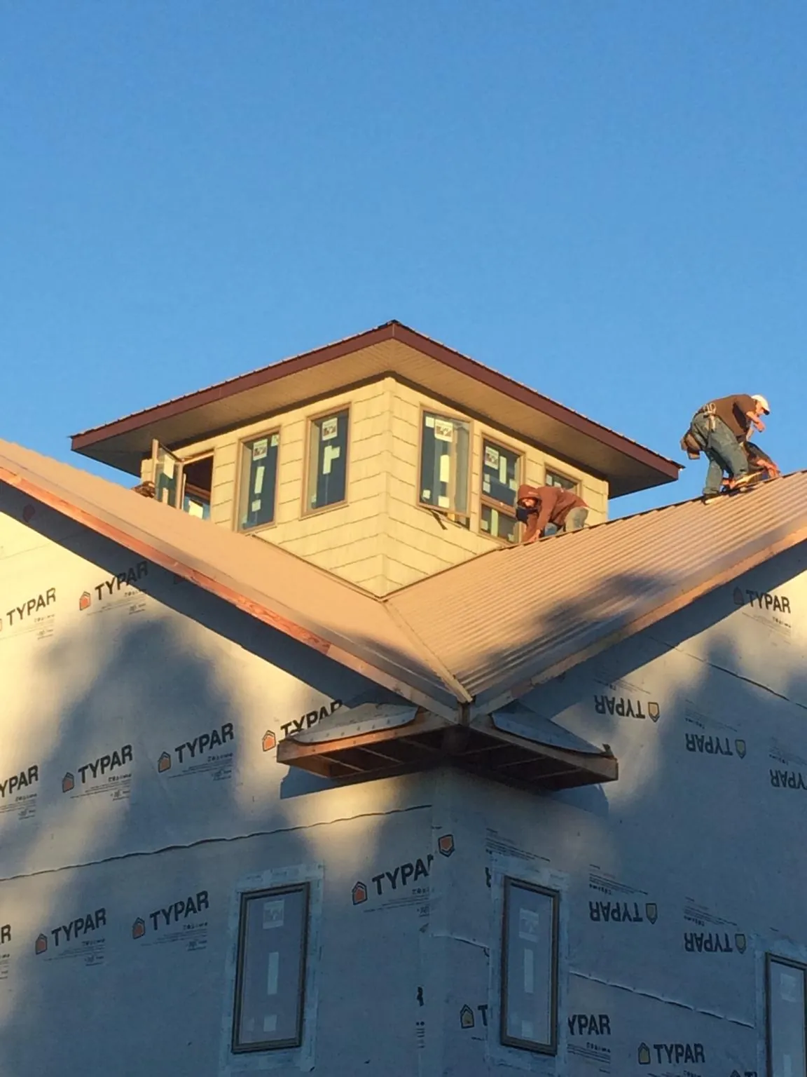 Roofers working around a rooftop cupola on a new metal roof at sunset — Roof Waterproofing in Bergen by Roofing Brothers